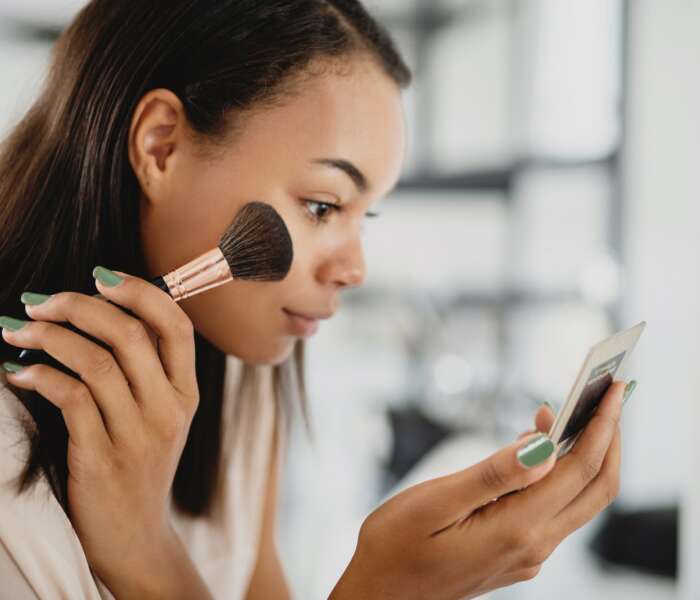 Beautiful young woman applying make up.