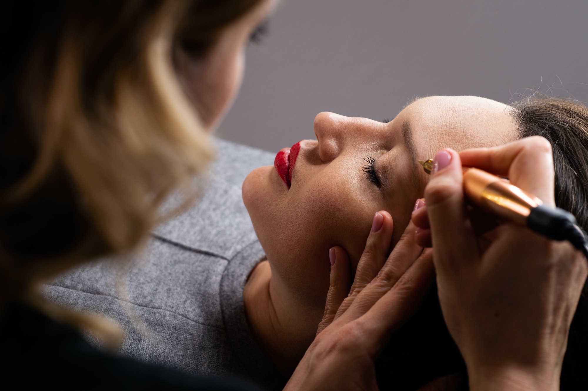 Eyebrows make up process. Make-up artist in beauty studio doing makeup for beautiful girl.