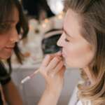 Make up artist applying professional makeup on woman using beauty products.